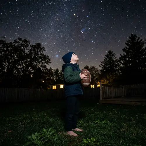 Child Gazing at Stars While Holding Football