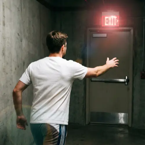 Caucasian Male Sprinting Towards Glowing 'Exit' Sign