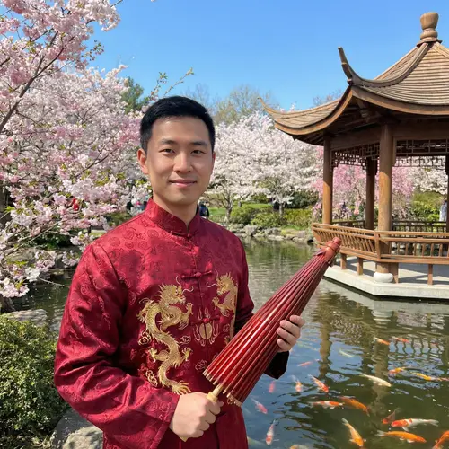 Traditional Chinese Man in Red Robe with Parasol in Cherry Blossom Garden