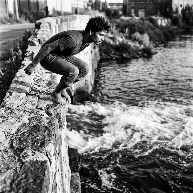 Dramatic Man Suspensefully Perched on Wall Over River | Canon EOS R6 50mm Lens