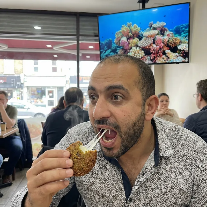 Man Eating Cheese-Stuffed Falafel with Screen Man Eating Cheese-Stuffed Falafel with Screen