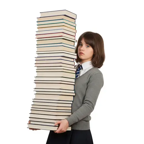 Young Girl with Bushy Brown Hair Carrying Impressive Stack of Books