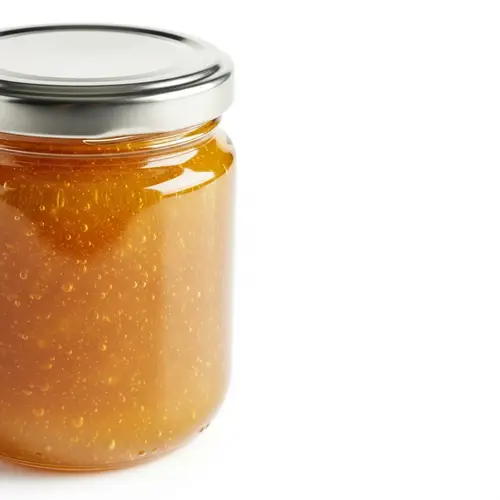 Golden Honey Jam in Glass Jar on White Background