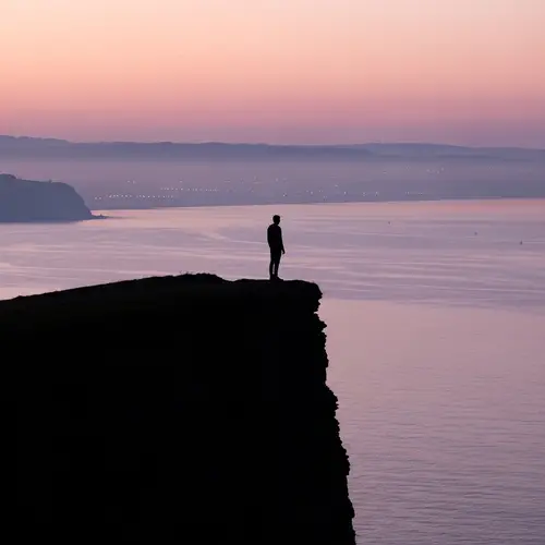 Dark Silhouette on Majestic Cliff Overlooking Lilac Hills and Ocean View