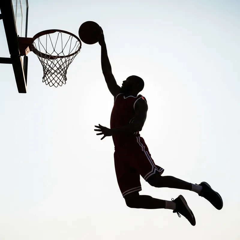 Silhouette of Basketball Player Going for Layup at Rim
