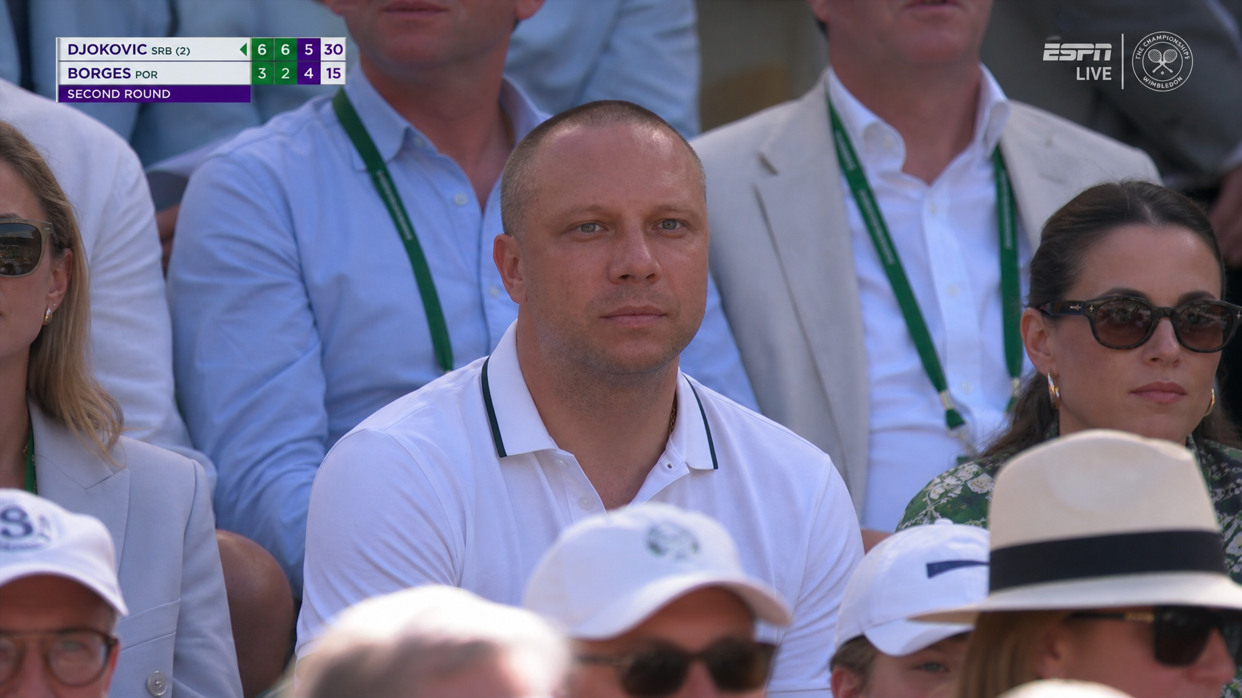 AI Wimbledon tennis fan cam image in a crisp white polo seated on Centre Court with set and game scoreboard overlay