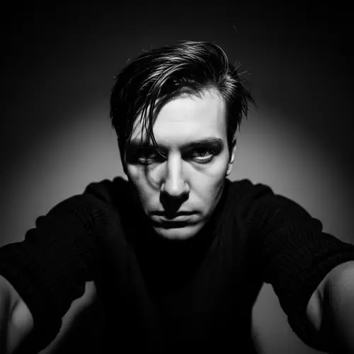 Introspective Black and White Self-Portrait in Dimly Lit Room