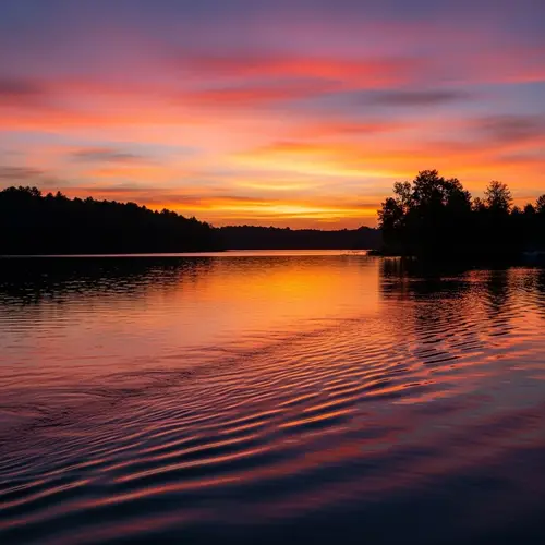 Tranquil Sunset Scene Over Lake with Silhouetted Trees