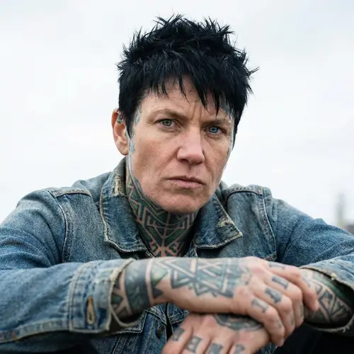 Masculine-Presenting Female Figure with Vibrant Tattoos and Striking Eyes