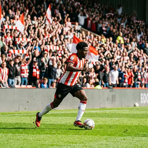 Professional Football Player Running on Green Field with Soccer Ball