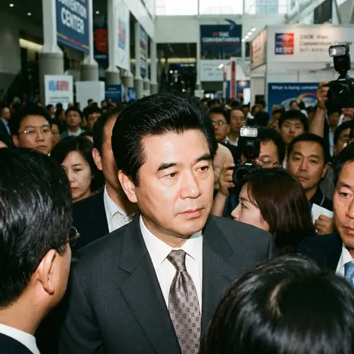 Middle-Aged Asian Man in Formal Suit at Busy Event