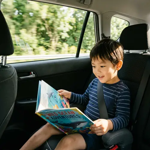 Asian Pre-Schooler Reading Book in Car | Educational Journey