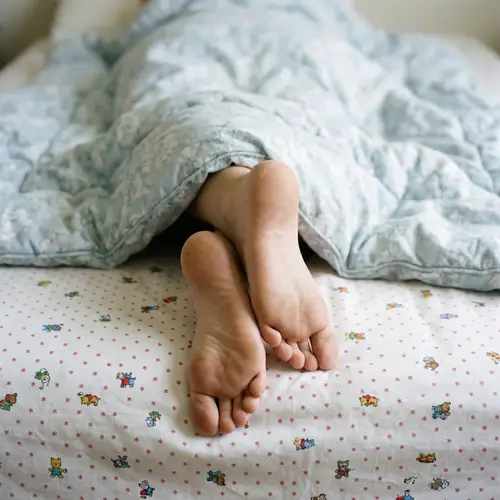 Close-Up of Bare Feet on Cozy Bed