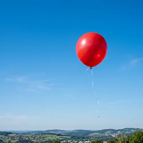 Vibrant Red Balloon Floating in Clear Azure Sky