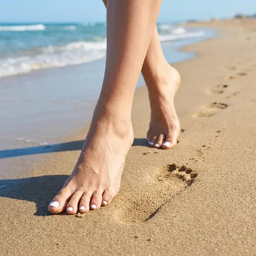 Beautiful Woman's Feet Walking on the Beach