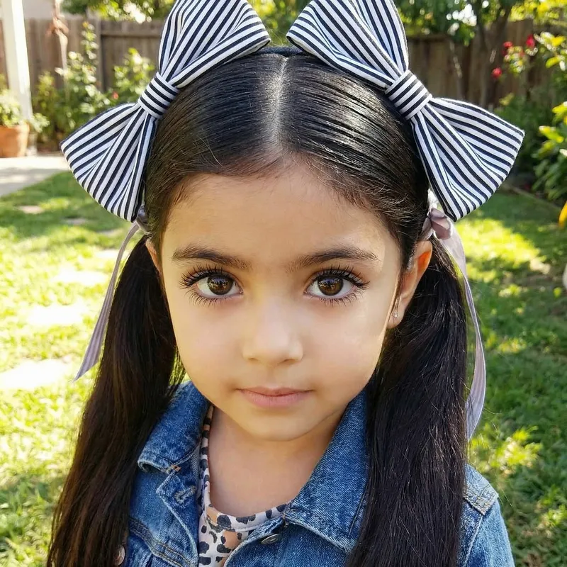 Adorable Girl with Long Black Hair in Dual Ponytails and Striking Brown Eyes