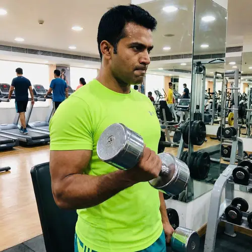 Fit South Asian Man Lifting Silver Dumbbell in Neon Green Apparel