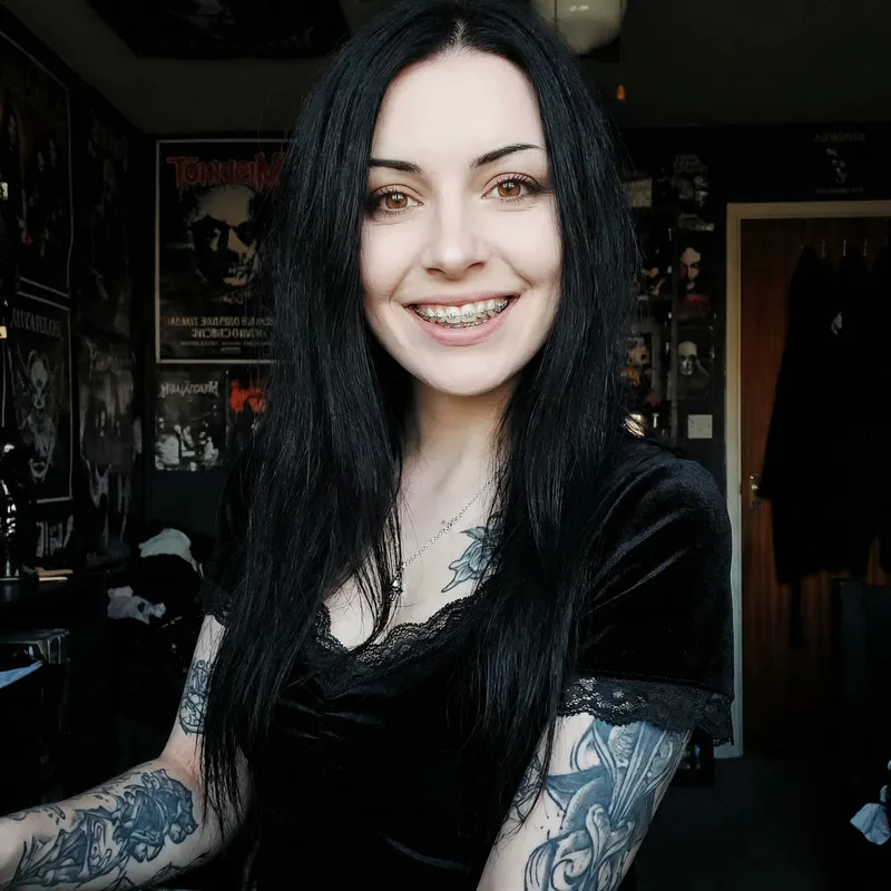 Confident Pale Goth Woman with Tattoos and Braces