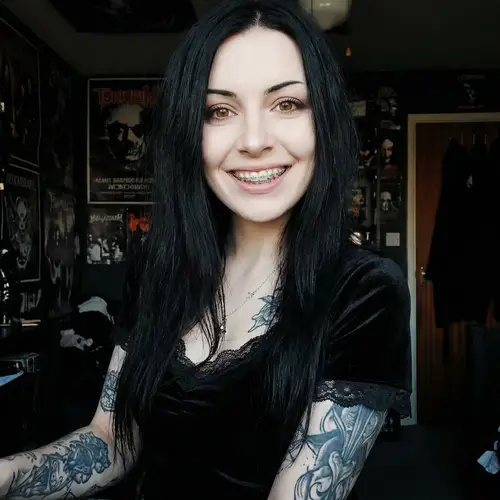 Confident Pale Goth Woman with Tattoos and Braces