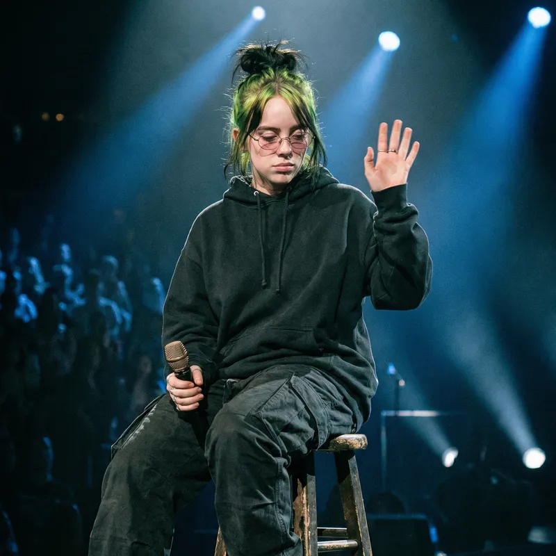 Billie Eilish: Young Woman with Green and Black Hair Performing on Stage