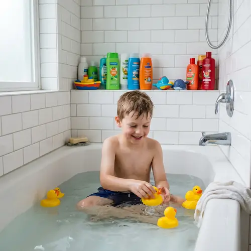 Caucasian Boy in Swimming Trunks Playing in Bathtub
