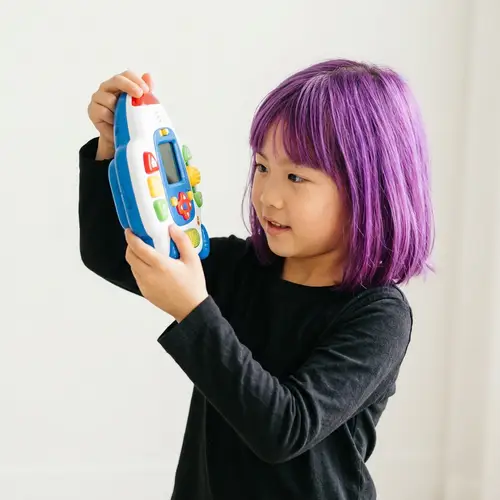 Young East Asian Girl with Vibrant Purple Hair Engaging with Toy