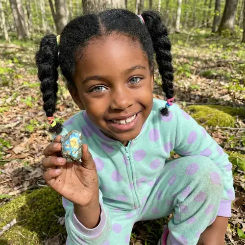 Young Black Girl with Joyful Expression Holding Magical Stone