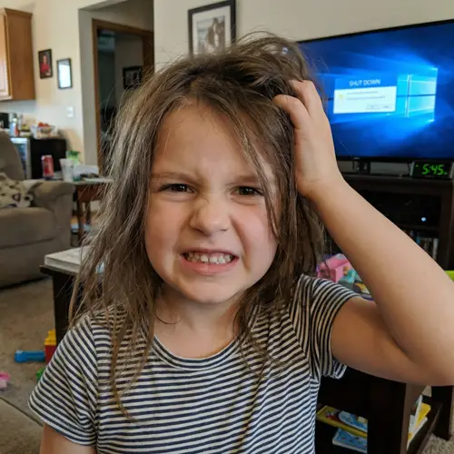 Young Girl with Funny Grimace Touching Head