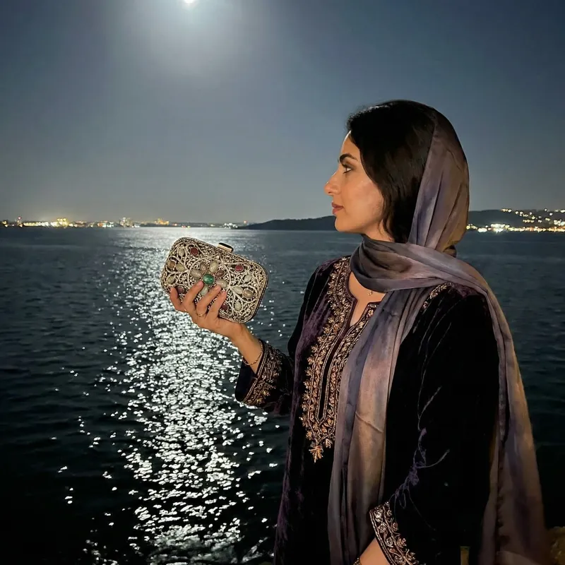 Elegant Woman Admiring the Sea at Night with Designer Purse