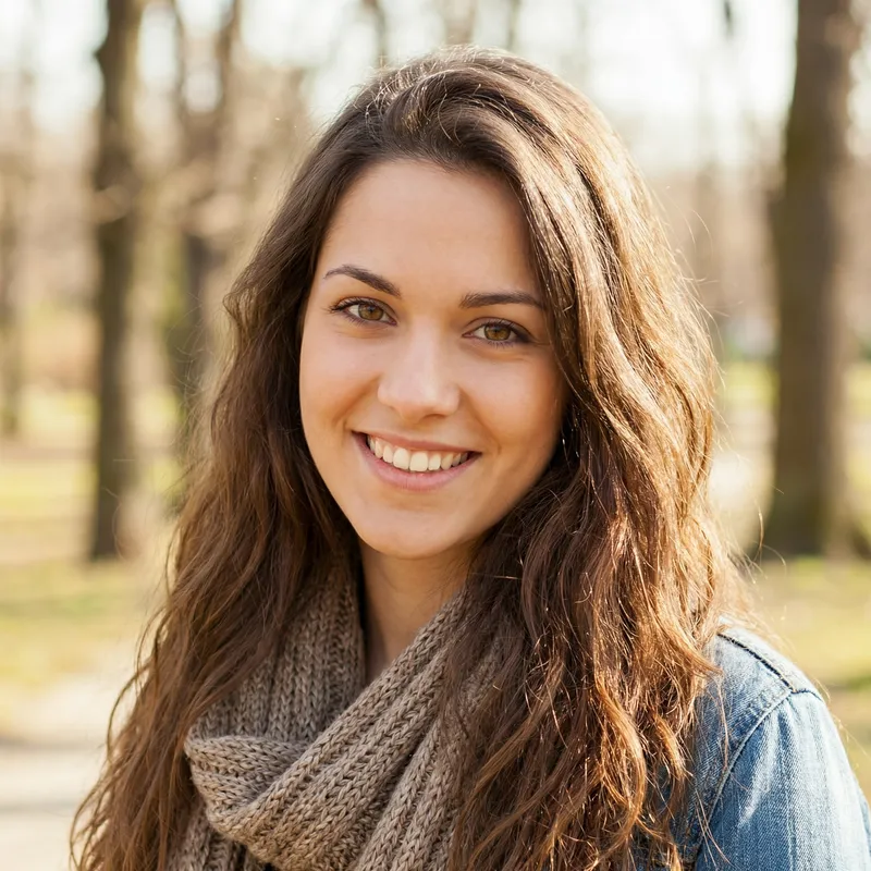 Smiling Young Woman with Wavy Brunette Hair and Almond-Shaped Brown Eyes