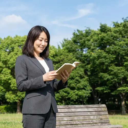 Professional Asian Woman Enjoying Book in Serene Park Setting