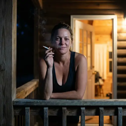 30-Year-Old Woman Smoking on Wooden Porch at Night