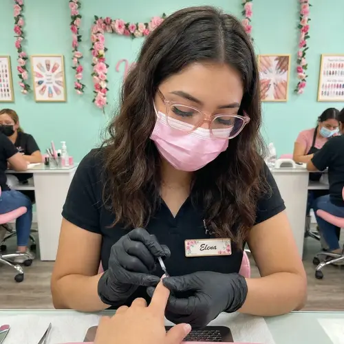 Young Hispanic Woman Manicurist with Long Hair and Pink Accessories