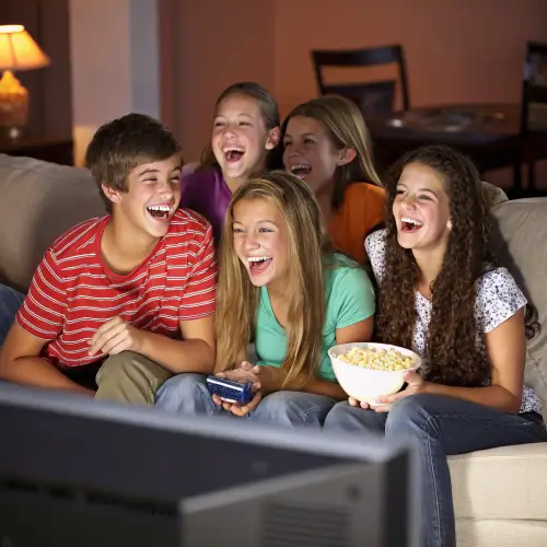 Teenagers Laughing on Couch While Watching TV
